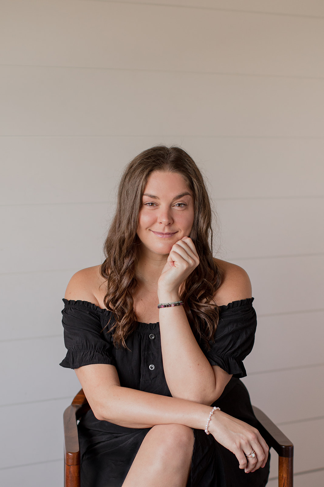 Heather Flynn seated and smiling warmly, resting her chin on her hand against a soft white wall
